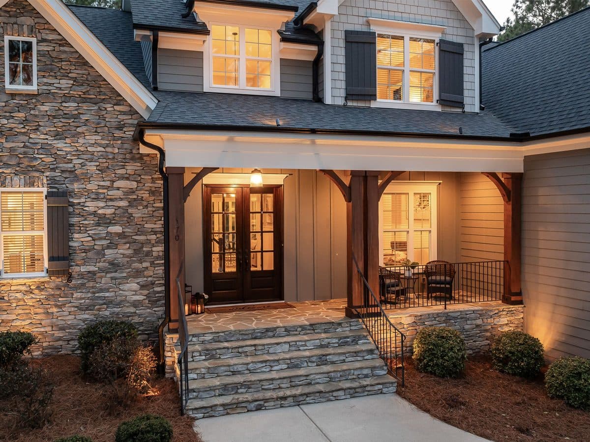 Stone-faced home entrance glowing with warm exterior lighting at dusk
